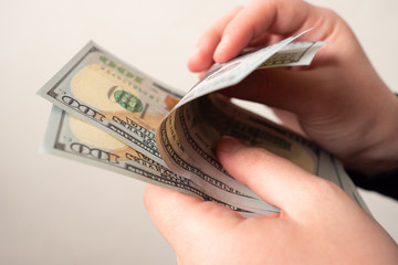 Hands of a man with dollars in close-up. The person counts the money. Purchase of goods and services. Family budget. Cost of living. Payment for necessary goods. The cost of the consumer basket.