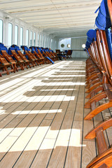 Wooden teak deck chairs and sun loungers with blue  pillows and upholstery on deck of luxury...