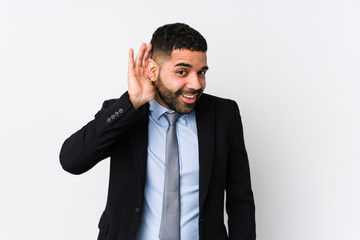 Young latin business woman against a white background isolated trying to listening a gossip.