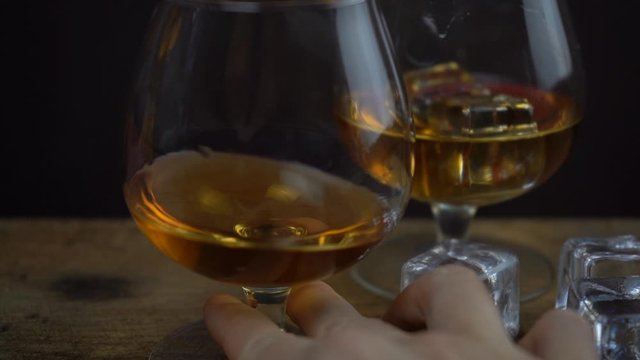 Slow motion footage of cognac or whiskey in a glass, alcohol tasting, glass of golden spirits in a hand
