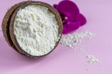 Collagen powder in half coconut with a spoon for measuring quantity. Extra protein intake. Natural supplements for beauty and health. Collagen based plant concept. Flatlay, top view.