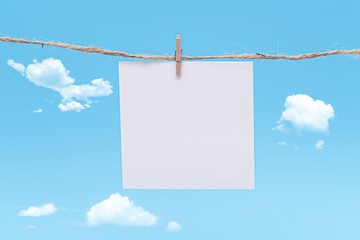 Blank Paper, hanging on rope by pin against blue Background, concept, office