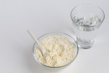 Collagen powder in a transparent bowl with a spoon for measuring quantity. Extra protein intake. Natural supplements for beauty and health. Collagen based plant concept. Flatlay, top view.