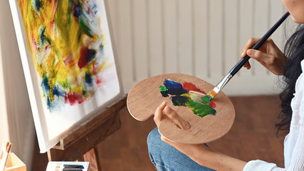 Cropped image of woman while sitting and drawing a watercolor at art studio.