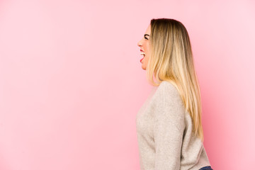 Middle age woman isolated on pink background shouting towards a copy space