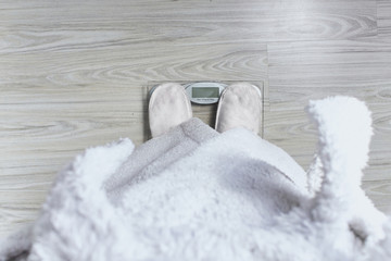 fat man in a white coat on a glass scale wooden parquet background. close up