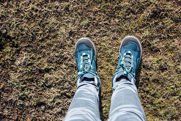 top view of trekking shoes on the soil background, female legs