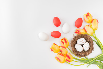 Flat lay easter composition with yellow tulips and eggs on a white background