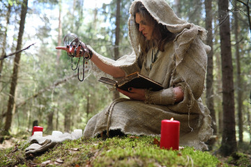 A man in a cassock spends a ritual in a dark forest