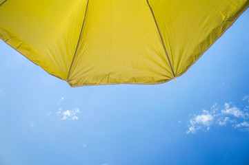 yellow umbrella on blue sky with clouds. Happy holiday vacation concept