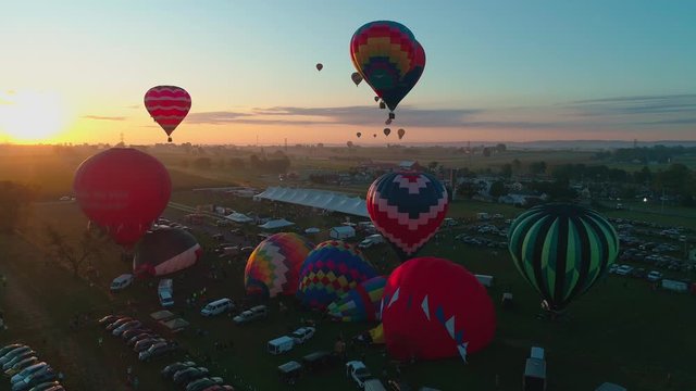 Aerial view of a hot air balloon festival early morning take off into the sun on a sunny summer day in Pennsylvania countryside
