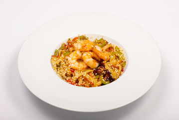 Asian style wheat noodles with shrimp, sweet peppers, sesame seeds and soy sauce in a white plate on a white background