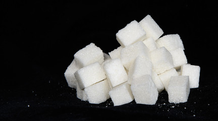 Cube sugar on a black background. Concept - obesity, diabetes, diet