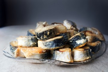 Fried fish on a glass dish on a dark background