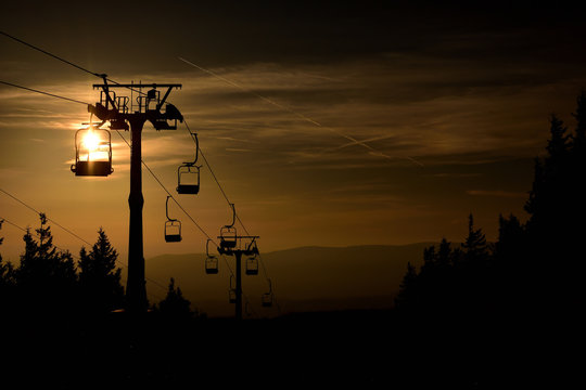 Ski chair lift cableway in the mountains at orange sunrise
