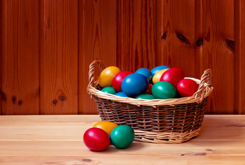 Easter eggs in wicker basket on wooden table. View with copy space.