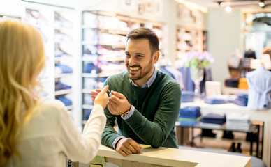 Handsome young man paying with credit card in the clotging store