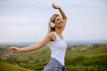 Happy young woman in nature listening to music on headphones