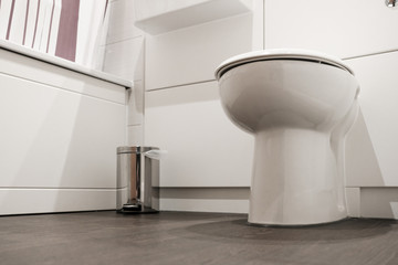 Low level view of a modern bathroom and ceramic toilet seen in a modern hotel. The wooden flooring...