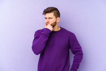 Fototapeta premium Young caucasian man isolated on purple background contemplating, planning a strategy, thinking about the way of a business.