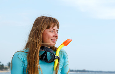 portrait of young diver girl with a snorkel and mask against the sky and sea