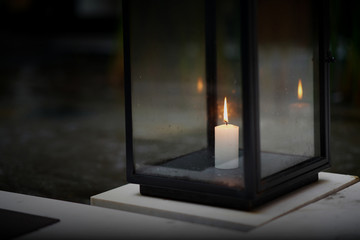 Candle in glass housing on floor in dark time with flame