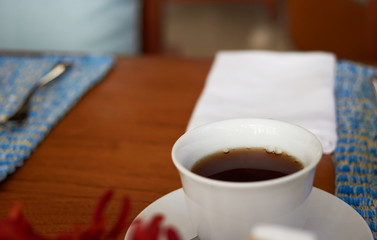 Tea in white cup on blur dining table