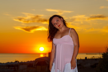 Fototapeta na wymiar Woman in a white dress on a background of the sea at sunset.