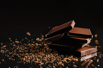 Slices of milk chocolate on a black background in the studio.