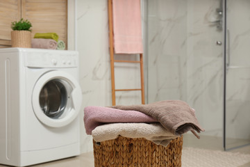 Wicker basket with laundry and washing machine in bathroom