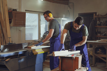 Professional carpenters working with wood in shop
