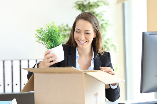 Happy businesswoman taking off belongings from box at office