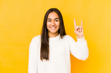 Young woman isolated on a yellow background showing a horns gesture as a revolution concept.