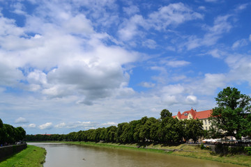 Fototapeta na wymiar river and embankment, blue sky, white clouds, linden trees, Uzhhorod, Ukraine