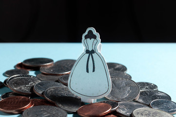 decorative elegant white classic wedding dress clamp on pile with american dollars coins on blue...