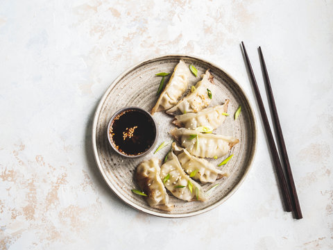 Chinese traditional dumplings - gyoza with pork and vegetables on a round plate with soy sauce in a bowl. Top view.
