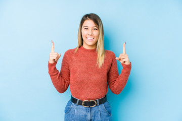 young caucasian woman posing isolated indicates with both fore fingers up showing a blank space.