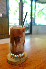 Iced Thai milk tea with beautiful texture in glass on wood table