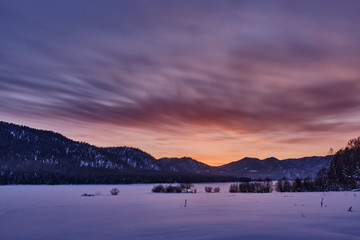 Winter mountain landscape. Orange-purple winter sunset in the mountains. Republic of Altai. Russia