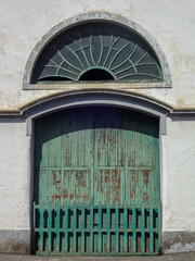 Vintage green door and round window in an old spanish house