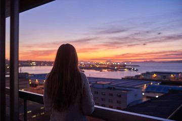 Young woman contemplating the sea from a balcony