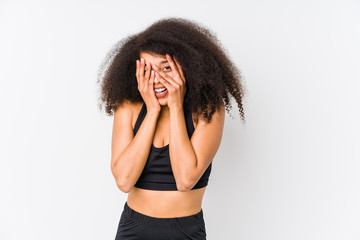 Young african american sporty woman blink through fingers frightened and nervous.