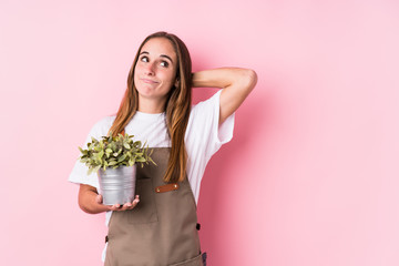 Young gardener caucasian woman isolated touching back of head, thinking and making a choice.