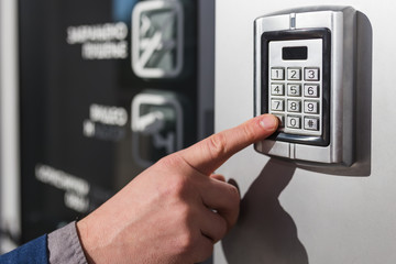 Close up of businessman hand entering security system code.
