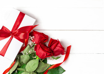 Three red roses, gift with red ribbon on the white wooden background. Women's day, mother day,...