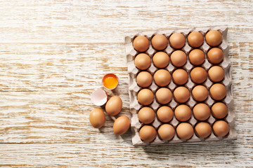 organic  eggs in a cardboard tray on a white wooden table, top view.