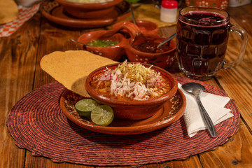 Red pozole with lettuce, oregano, onion, grated radish, toast and lemon. Typical Mexican food made...
