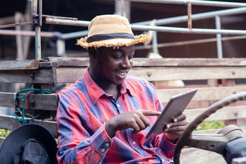 Fototapeta na wymiar African farmer man using tablet with happy and smiling on old tractor