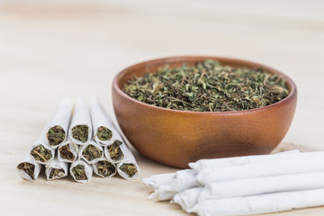 Marijuana or weed or cannabis on wooden bowl and in the rolled joint.