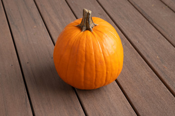 Cute round pumpkin sitting on a wood deck
